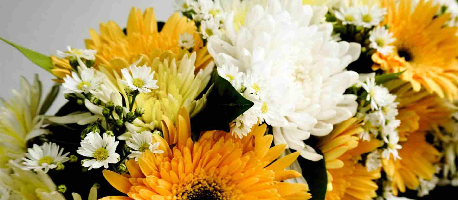 ดอกไม้สีขาวและสีส้มแซมด้วยดอกไม้ขนาดเล็กเป็นส่วนหนึ่งของพวงหรีดดอกไม้ที่จัดวางอย่างมีศิลปะและสวยงาม