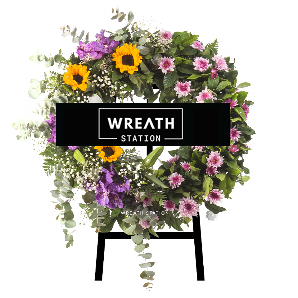 พวงหรีดดอกไม้สดทรงกลม โดดเด่นด้วยโทนสีม่วง แซมด้วยสีชมพูและเหลือง จาก Wreath Station