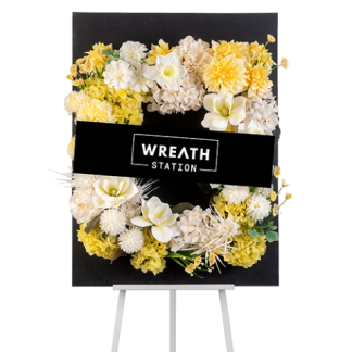 พวงหรีดดอกไม้ประดิษฐ์โทนสีเหลือง จัดบนกระดานดำทรงสี่เหลี่ยม ประกอบด้วยไฮเดรนเยีย แมกโนเลีย มัมปิงปอง เบญจมาศ เอมมี่ และดาเลีย